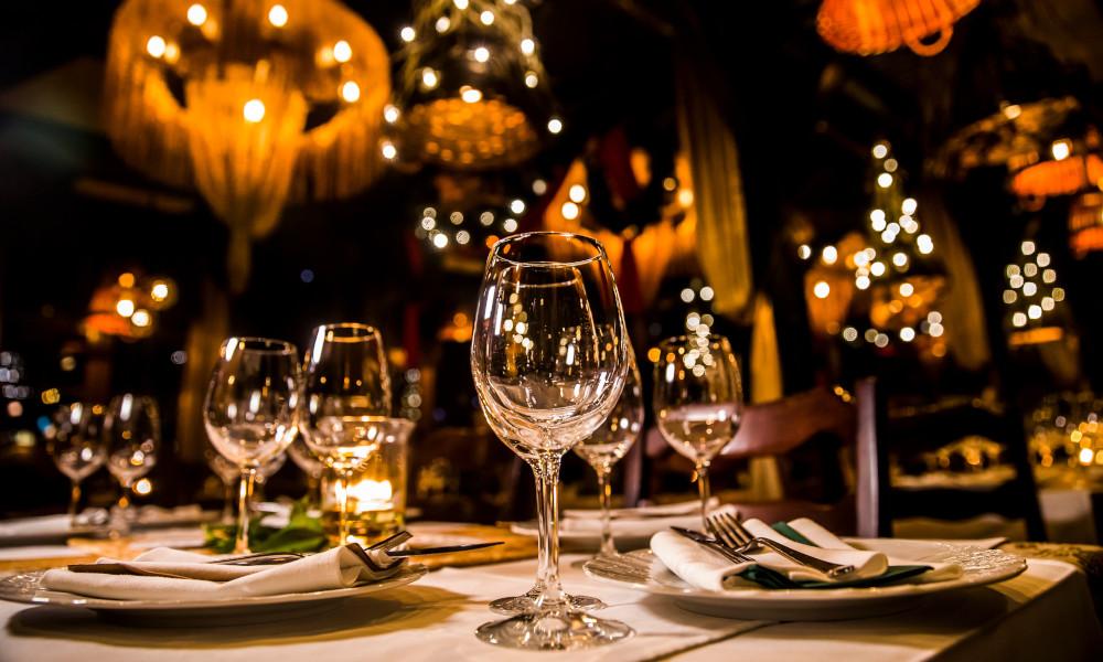 Table at restaurant with wine glasses, plates and silverwear set.